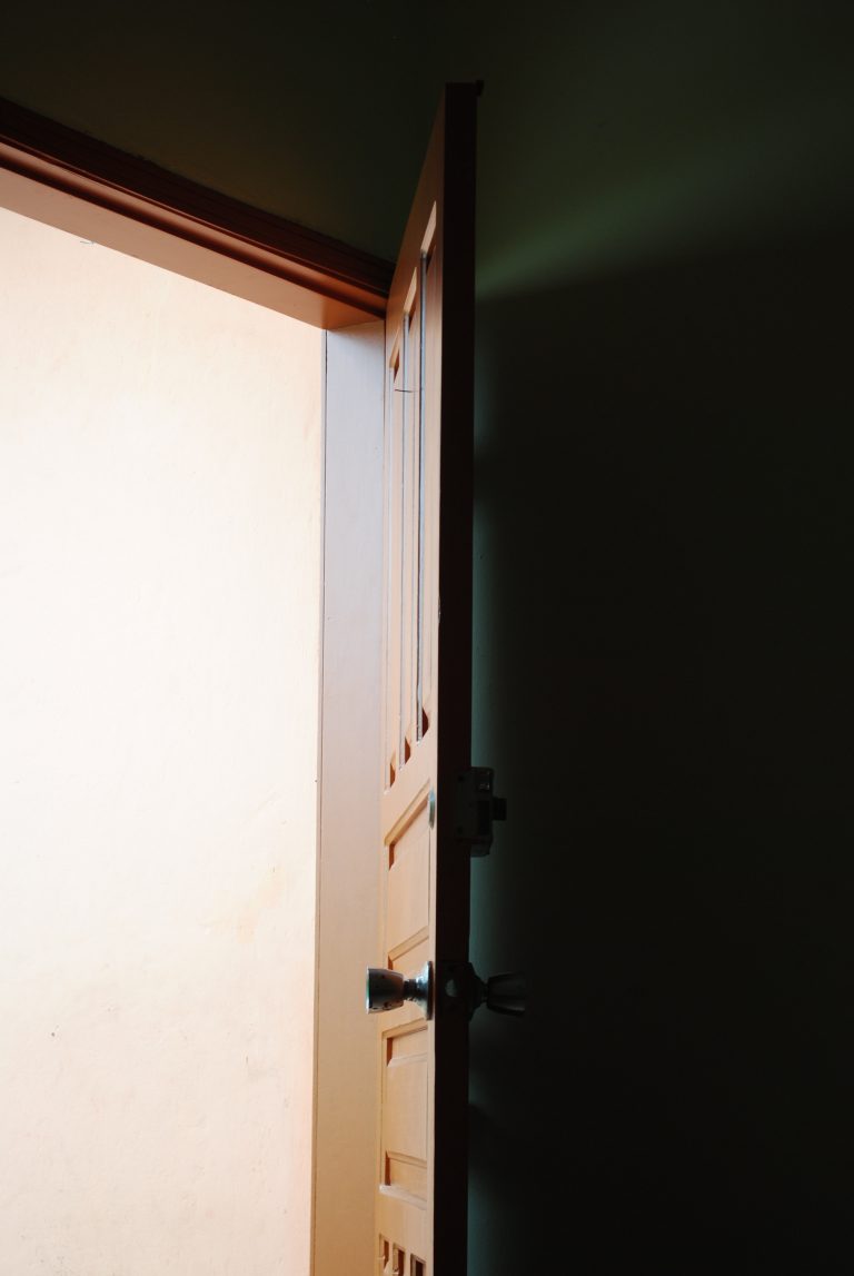 Brown door slightly open, allowing light in