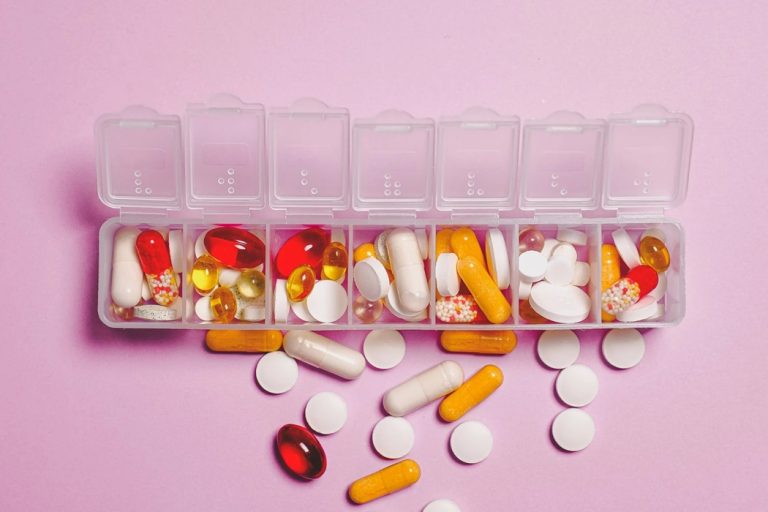 Pill organizer with multicolored pills spilling out of it.