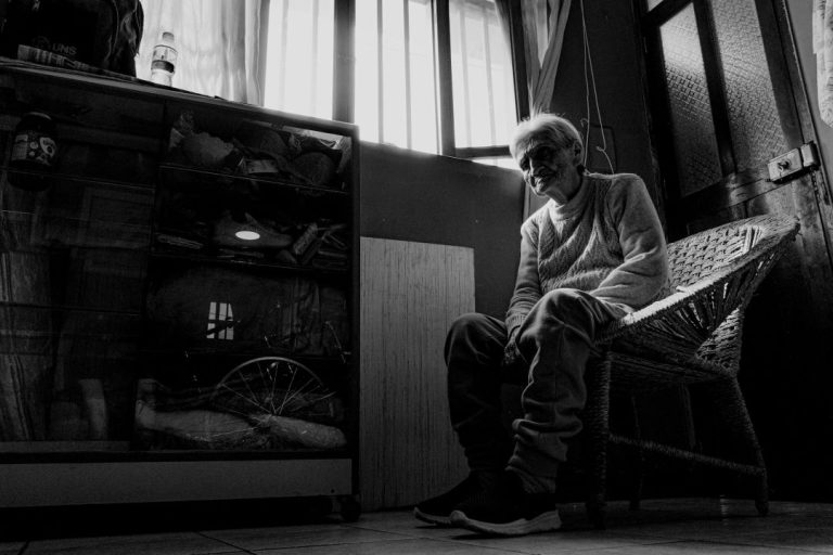 Old woman sitting in chair, black and white photo