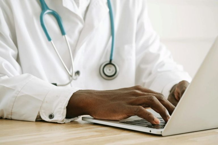 Close-up of doctor's hands over laptop