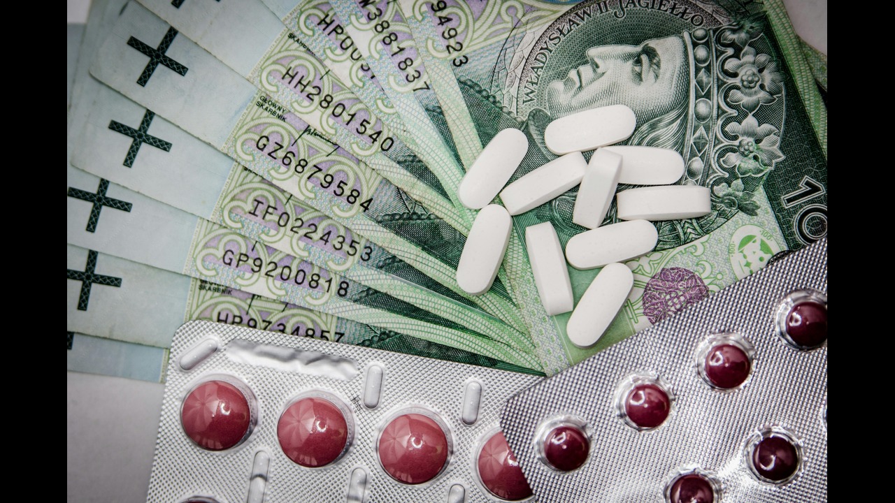 an image containing white loose white oval pills next to sleeved red pills, all sitting on top of currency