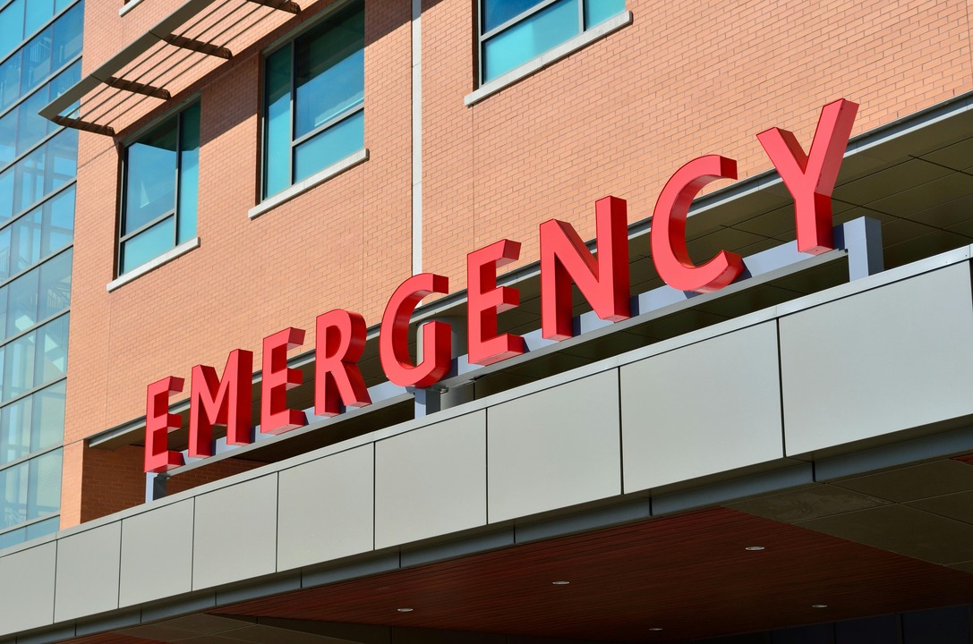 the word "emergency" written in red, in all caps, on a hospital entrance