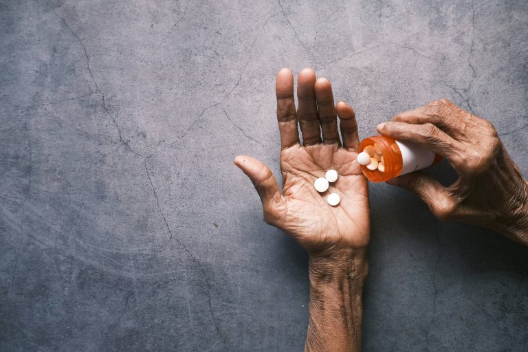 An aged hand, holding pills