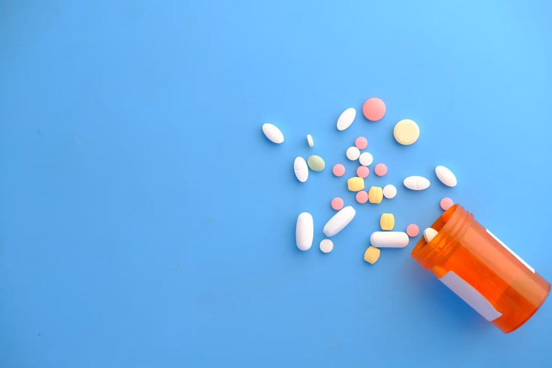 Spilled prescription drug bottle on a blue background